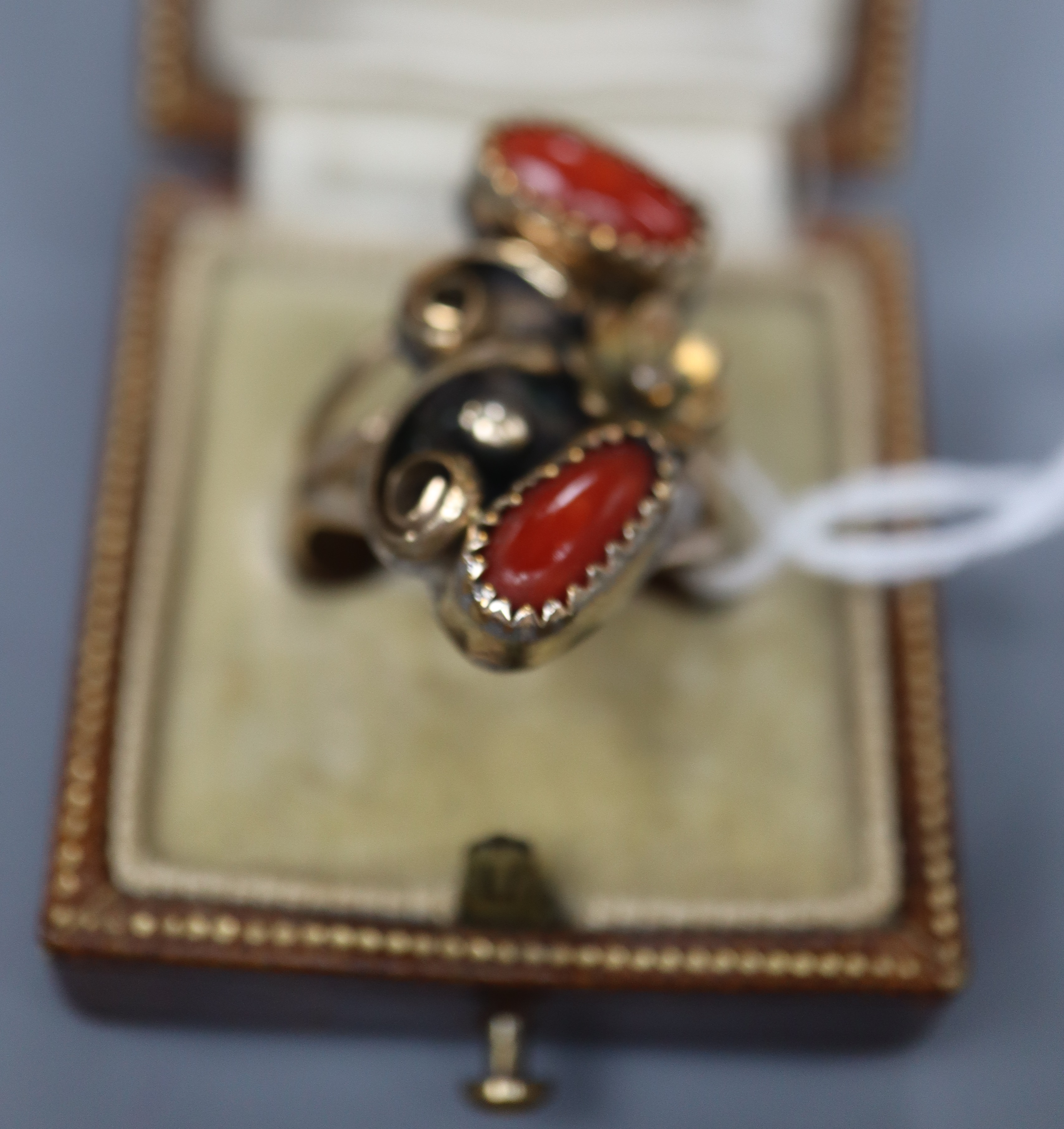An Arts & Crafts yellow and white metal and two stone cabochon coral set triple shank dress ring, size O,